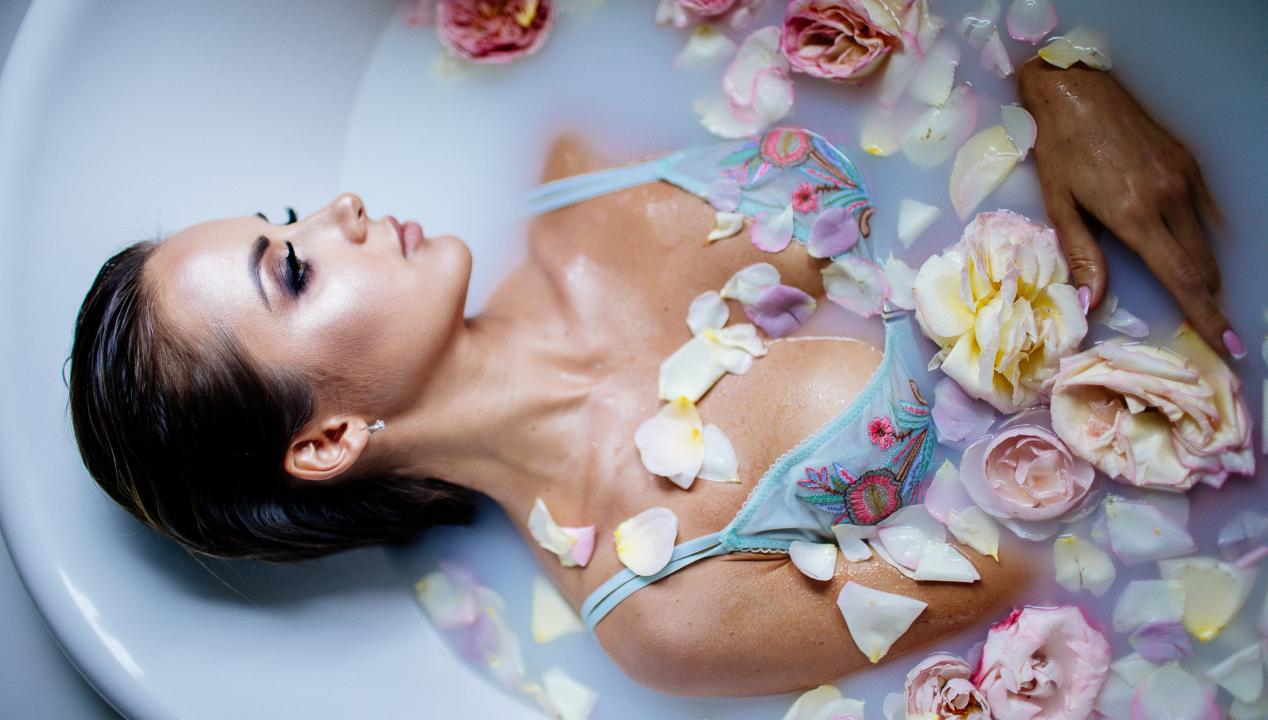 Frau badet in Blüten und Milch, die an Sperma erinnert