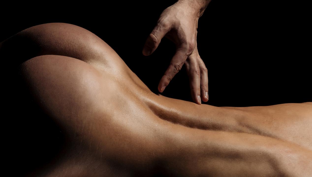 Männerhand liebkost den Rücken und runden Hintern einer nackten Frau