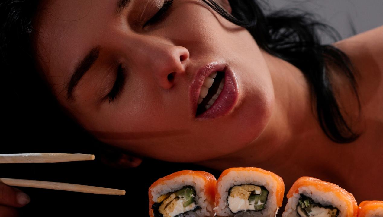 sexy junge Latina isst Sushi als aphrodisierendes Lebensmittel auf sinnliche Weise