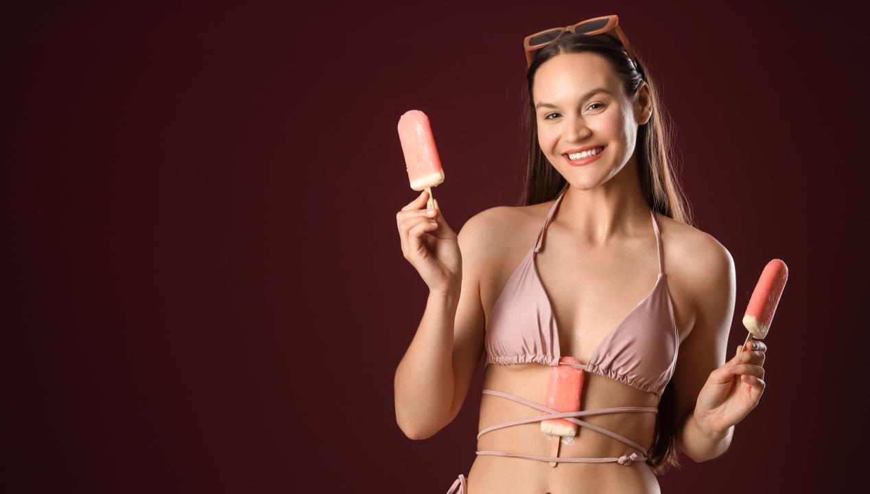 eine Frau im rosa Bikini steckt sich vor dem Amateurporn-Dreh mehrere Eis in die Bänder des Bikinis